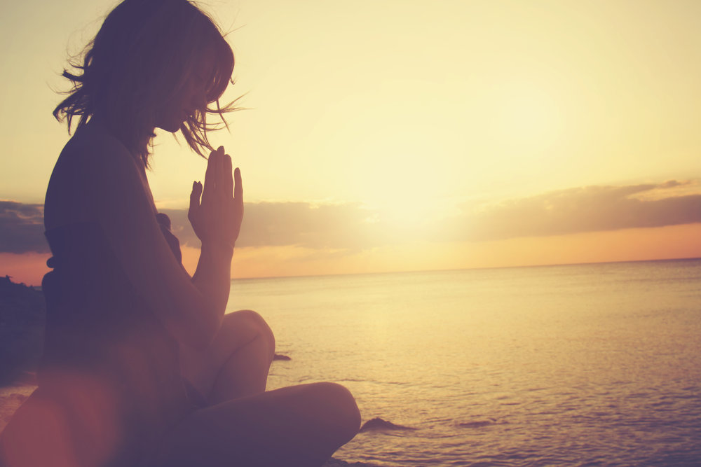 Young woman practicing yoga on the beach.