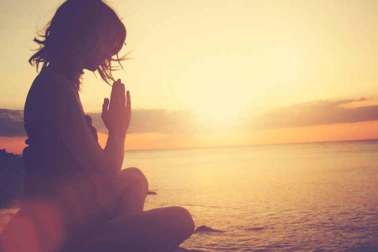 Young woman practicing yoga on the beach.